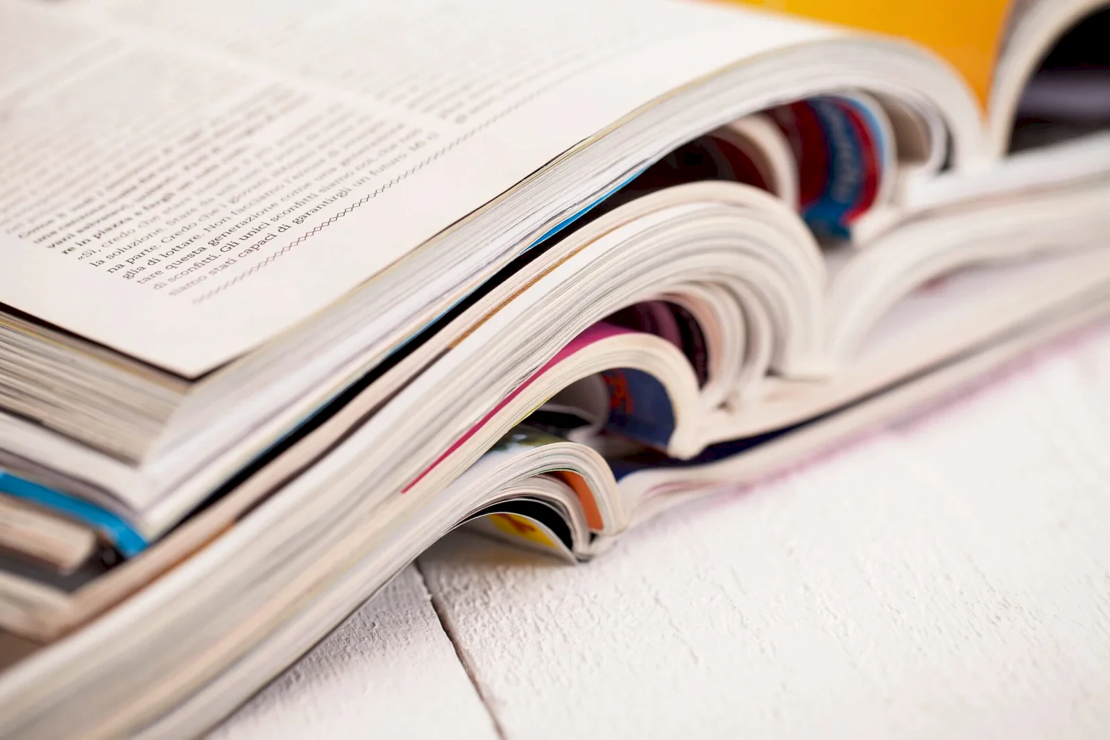 Pile of colorful magazines on a white table